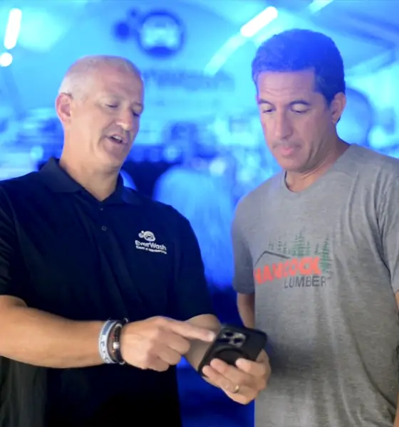 An EverWash team member showing a car wash operator the app